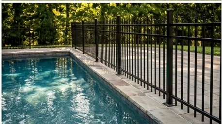 Black aluminum pool fence enclosing a backyard swimming pool and deck