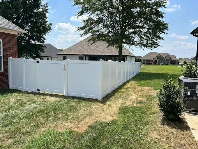 White vinyl privacy fence panels behind a mowed lawn